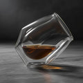 Clear glass with a geometric design filled with amber liquid on a white background