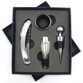 A stainless steel wine accessory set displayed in a black gift box, including a corkscrew, a wine stopper, a bottle aerator, and a round ring accessory, on a white background.