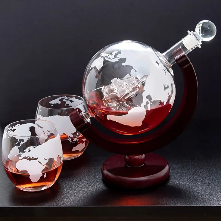 Globular decanter with world map design, filled with a red liquid, accompanied by two matching glasses on a dark background.