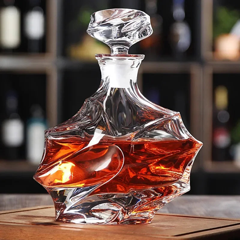 Glass decanter with a swirling design filled with a amber liquid on a wooden surface.