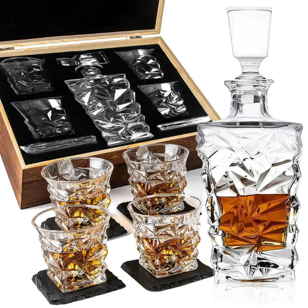 A clear crystal decanter with a stopper and four matching crystal tumblers, shown with a wooden presentation box and black coasters on a white background.