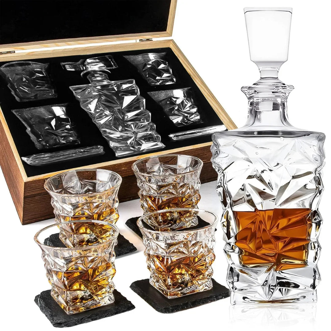 A clear crystal decanter with a stopper and four matching crystal tumblers, shown with a wooden presentation box and black coasters on a white background.