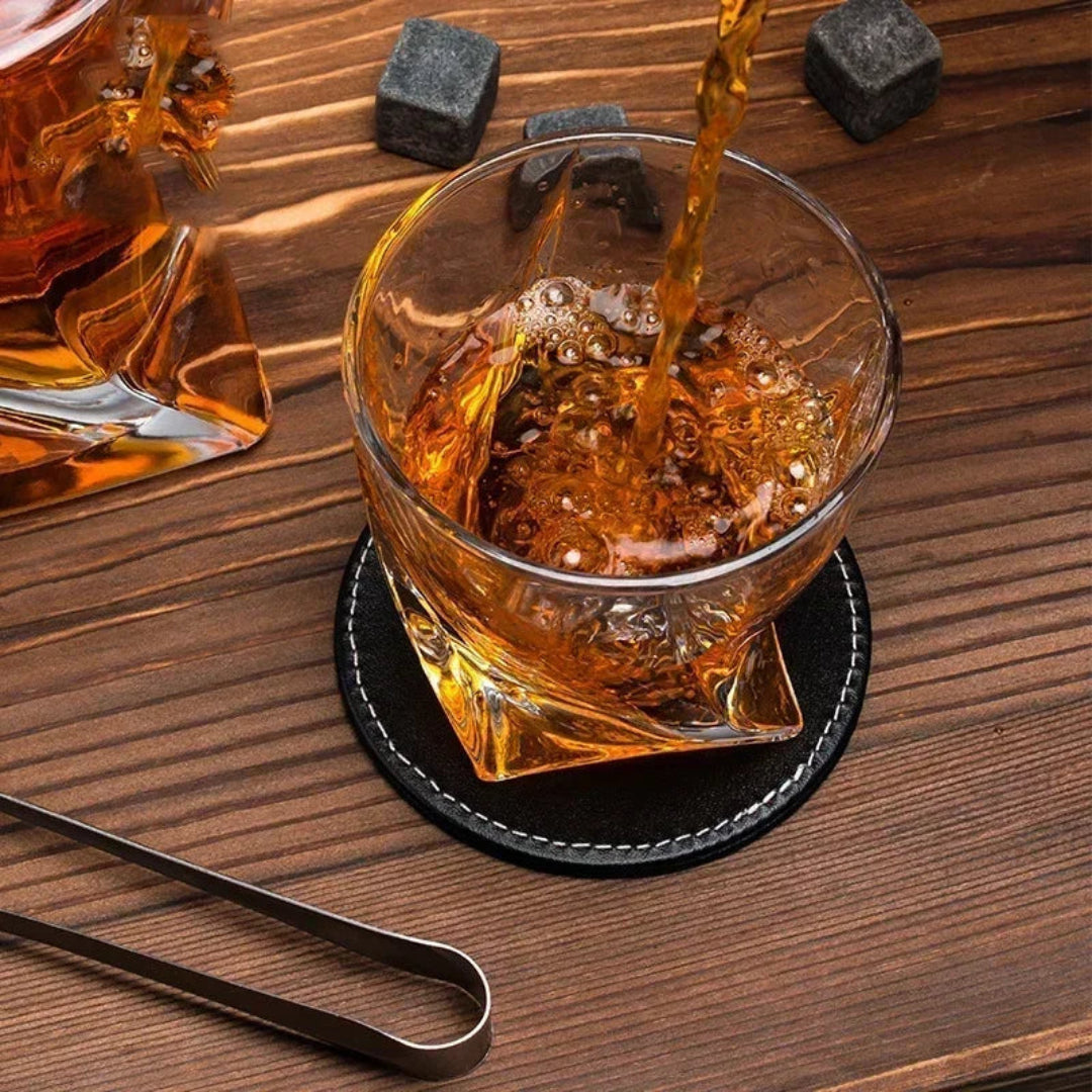 Whiskey being poured into a glass on a wooden surface with a coaster.
