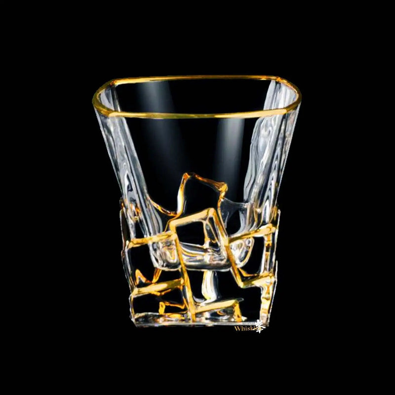 Clear glass tumbler with gold rim and intricate designs on a black background