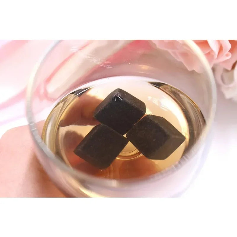 Black gemstones in a glass of liquid with a blurred background