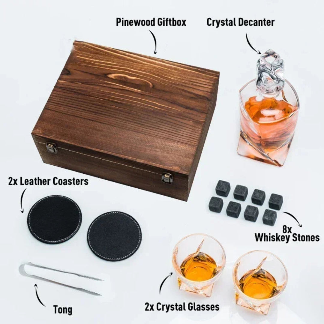 Whiskey accessories set with a pinewood giftbox, crystal decanter, leather coasters, whiskey stones, and glasses on a white background.
