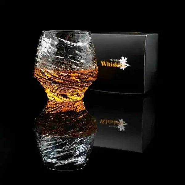 Crystal whiskey glass with liquid inside, placed on a reflective surface with a black background.