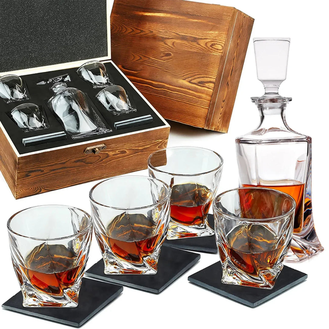 A whiskey decanter set with four clear cut-glass tumblers, a clear decanter, black coasters, and a wooden presentation box with a black foam insert, shown on a white background.
