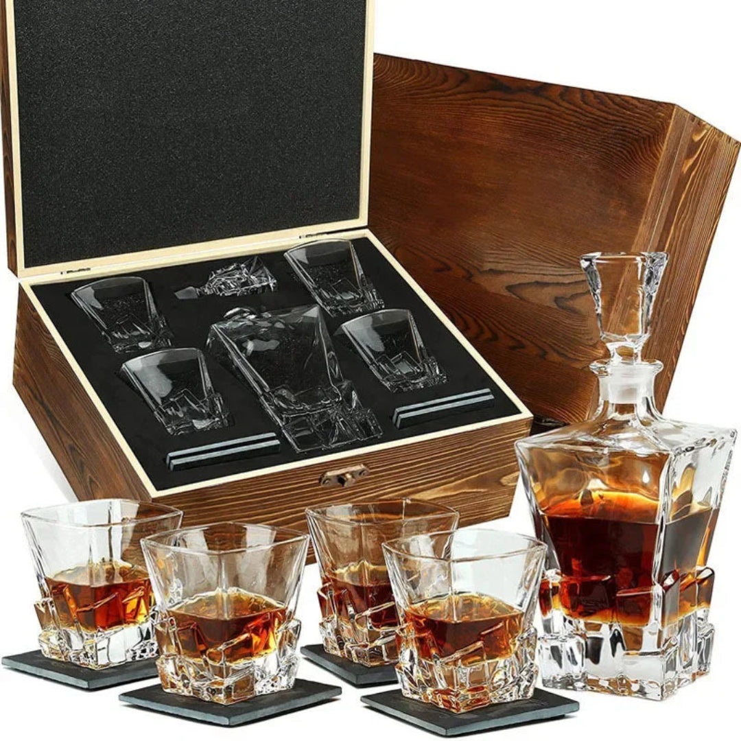 A whiskey set including a clear glass decanter, six faceted whiskey glasses, four coasters, and an open wooden presentation box with a black insert, shown on a white background.